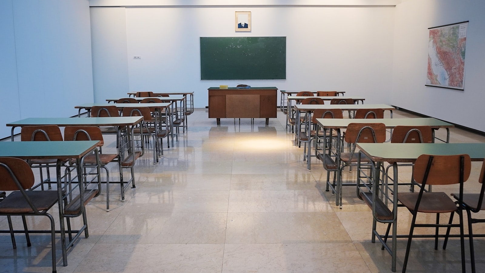 Lyst klasselokale med rækker af skoleborde og grøn tavle — institutionsrengøring