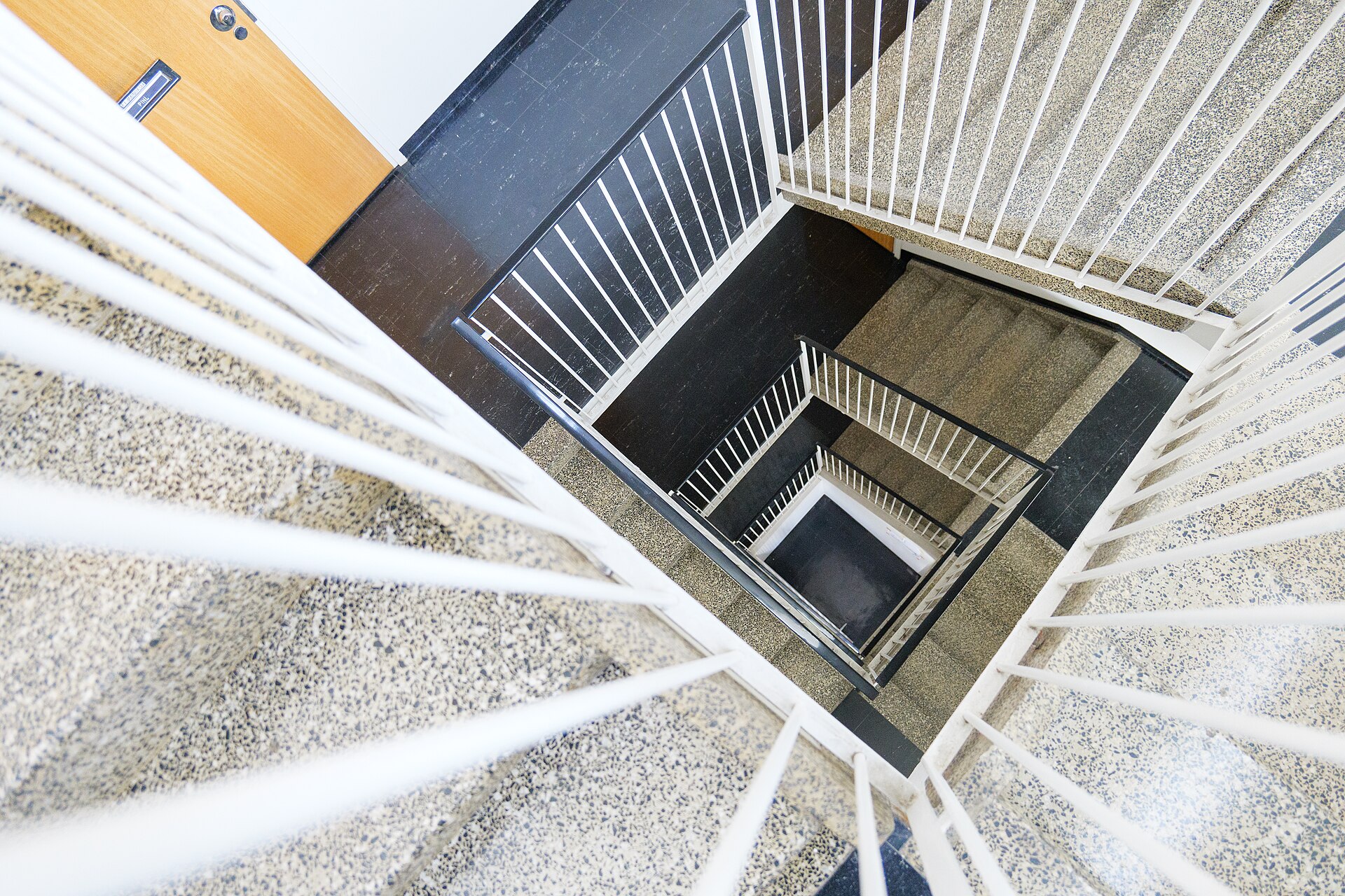 Kig ned gennem en lys trappeopgang med terrazzo-trin — ejendomsservice